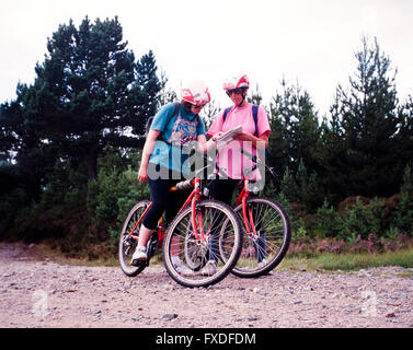 Due giovani donne in mountain bike controllare una mappa, Cairngorms, Aviemore Scozia,UK. Foto Stock