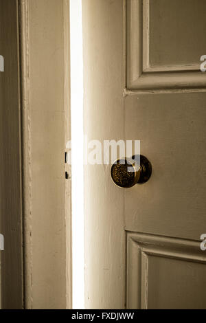 La luce che arriva attraverso la porta aperta, con pannelli interni porta con maniglia in ottone Foto Stock