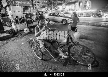 La città di Yangon, Rangon City, Myanmar, un uomo con risho nella città, sulla strada di sera. Foto Stock