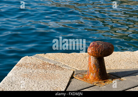 Rusty bollard sull'angolo del dock nel porto Foto Stock
