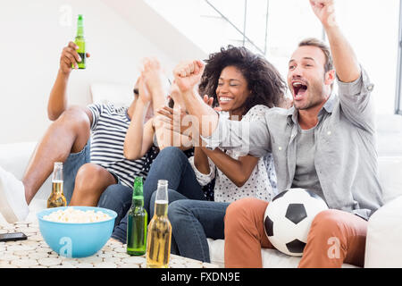 Emozionato amici tifo mentre guardi la televisione Foto Stock