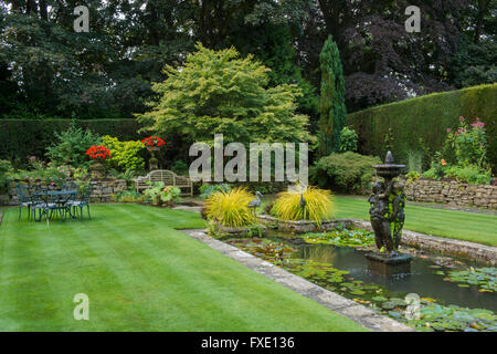 Una bella, privato tradizionale, paesaggistico, country Garden, West Yorkshire, Inghilterra - laghetto ornamentale, fontana e prato in estate. Foto Stock