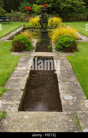 Una bella, privato tradizionale, paesaggistico, country Garden, West Yorkshire, Inghilterra - laghetto ornamentale, fontana e graminacee. Foto Stock