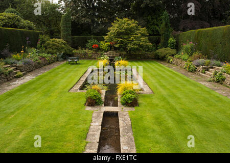 Una bella, privato tradizionale, paesaggistico, country Garden, West Yorkshire, Inghilterra - laghetto ornamentale, fontana, area con posti a sedere e prato a strisce. Foto Stock