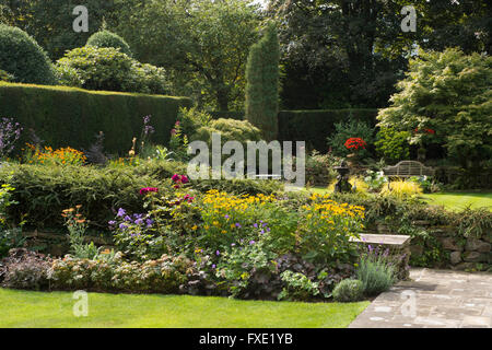 Una bella, privato tradizionale, paesaggistico, country Garden, West Yorkshire, Inghilterra - piante erbacee confine con piante fiorite, percorso e prato. Foto Stock