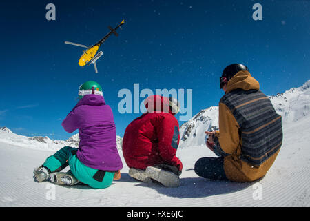 Un gruppo di sciatori e snowboarder sono riaccompagnati in elicottero in cima a una montagna nelle Alpi francesi. Foto Stock