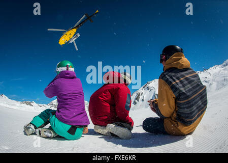 Un gruppo di sciatori e snowboarder sono riaccompagnati in elicottero in cima a una montagna nelle Alpi francesi. Foto Stock