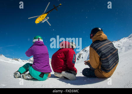 Un gruppo di sciatori e snowboarder sono riaccompagnati in elicottero in cima a una montagna nelle Alpi francesi. Foto Stock