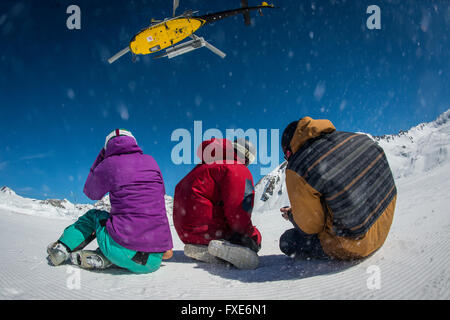 Un gruppo di sciatori e snowboarder sono riaccompagnati in elicottero in cima a una montagna nelle Alpi francesi. Foto Stock