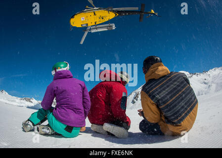 Un gruppo di sciatori e snowboarder sono riaccompagnati in elicottero in cima a una montagna nelle Alpi francesi. Foto Stock