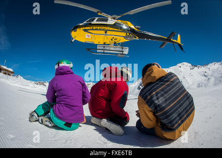 Un gruppo di sciatori e snowboarder sono riaccompagnati in elicottero in cima a una montagna nelle Alpi francesi. Foto Stock