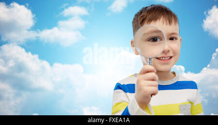 Happy little boy guardando attraverso la lente di ingrandimento Foto Stock