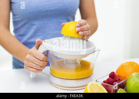 Close up della donna la spremitura di succhi di frutta a casa Foto Stock