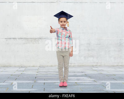 Felice ragazza nel corso di laurea hat mostra pollice in alto Foto Stock