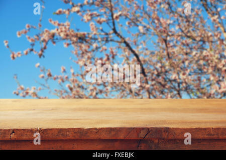 Rustico in legno tavolo di fronte a molla bianco fiori di ciliegio albero. vintage immagine filtrata. display del prodotto e concetto di picnic Foto Stock