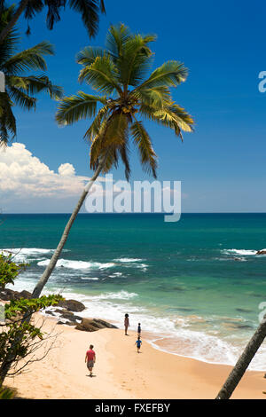 Sri Lanka, Tangalle, giovane famiglia rilassante sulla spiaggia tropicale idilliaco Foto Stock