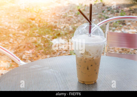 Bicchiere di plastica del caffè ghiacciato capuchino sul tavolo in metallo con luce solare al di sopra Foto Stock