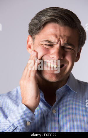 Ritratto in studio di uomo che soffre di mal di denti Foto Stock