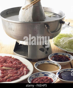 Mongolian hotpot, tagliata a fettine sottili di agnello, verdure e gli spaghetti in acqua bollente e servito con la schiera di salse Foto Stock