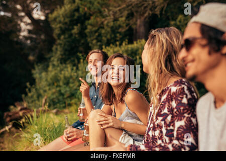Ritratto di Allegro giovani amici appendere fuori con birre. Gruppo di amici seduti all'aperto e divertirsi. Foto Stock