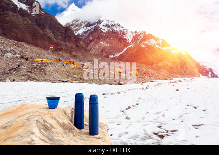 Due viaggi blu thermoses Thermo bottiglie e scodellino sulla pietra e sul Campo Base in alta montagna Foto Stock