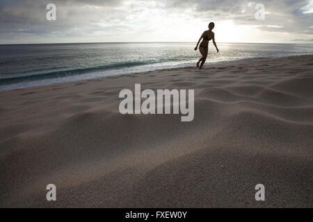 Giovane donna stretching e giocare al litorale, Keawaula Beach, West Oahu, Hawaii Foto Stock