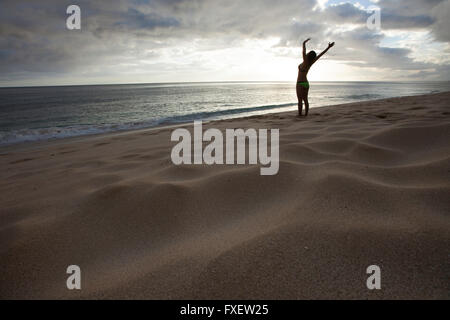 Giovane donna stretching e giocare al litorale, Keawaula Beach, West Oahu, Hawaii Foto Stock