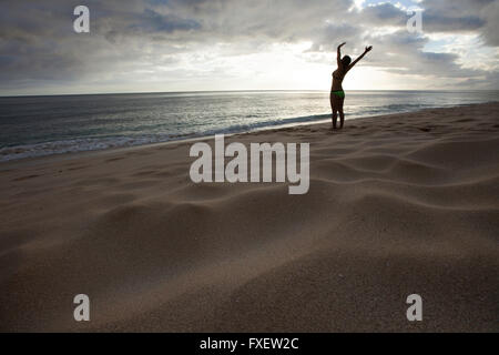 Giovane donna stretching e giocare al litorale, Keawaula Beach, West Oahu, Hawaii Foto Stock