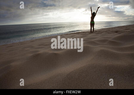 Giovane donna stretching e giocare al litorale, Keawaula Beach, West Oahu, Hawaii Foto Stock