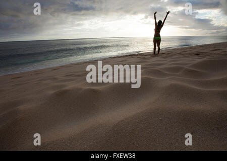 Giovane donna stretching e giocare al litorale, Keawaula Beach, West Oahu, Hawaii Foto Stock