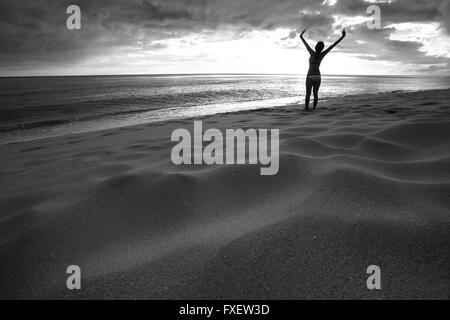 Giovane donna stretching e giocare al litorale, Keawaula Beach, West Oahu, Hawaii Foto Stock