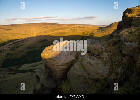 Gritstone rocce sulle colline sopra Hayfield nel Derbyshire. Nel tardo pomeriggio la luce del sole sulle colline. Foto Stock