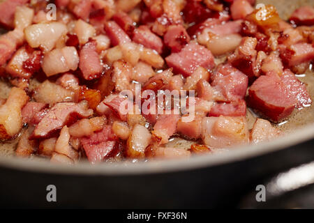 Bit di trito di pancetta friggere in una padella Foto Stock