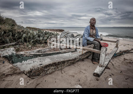 Mozambico, Africa, un pescatore in barca sulla spiaggia, spiaggia bianca, cielo nuvoloso. Foto Stock