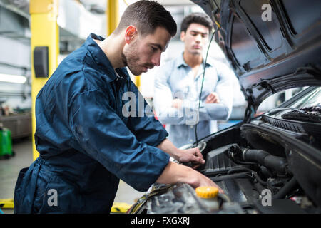 Esaminando meccanico auto a motore mentre il cliente permanente e la ricerca Foto Stock