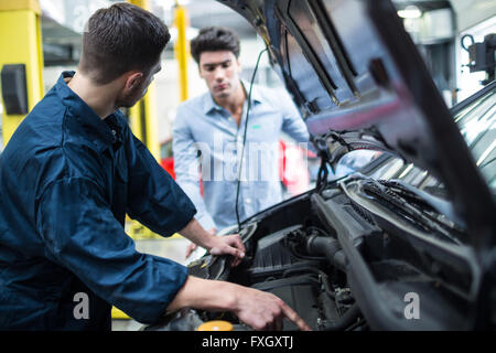 Il meccanico che mostra il cliente il problema con auto Foto Stock