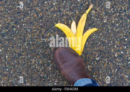 Uomo in procinto di scivolare e cadere su una buccia di banana Foto Stock