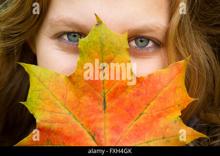 Chiudere fino a una giovane donna con colorati maple leaf in mano Foto Stock