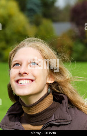 Giovane donna felice cercando in cielo Foto Stock