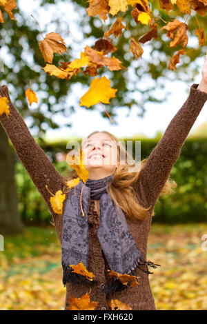 In autunno le foglie che cadono sulla felice giovane donna nella foresta Foto Stock