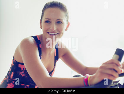 Donna sorridente riding cyclette in palestra Foto Stock