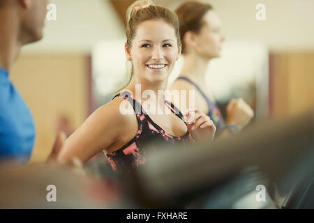 Donna sorridente jogging sul tapis roulant in palestra Foto Stock