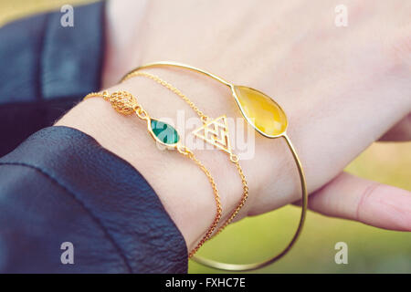 Femmina con mano tre golden bracciali Foto Stock