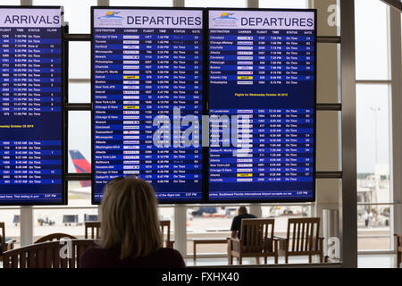 Donna che guarda un monitor di partenza a Southwest Florida airport Foto Stock