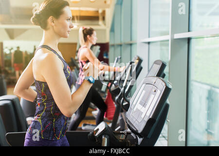 Donna focalizzato in esecuzione sul tapis roulant in palestra Foto Stock