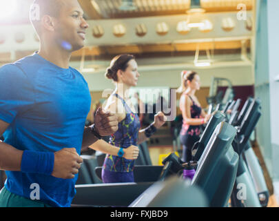 Uomo sorridente in esecuzione sul tapis roulant in palestra Foto Stock