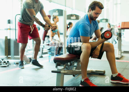 L'uomo facendo dumbbell riccioli bicipiti in palestra Foto Stock