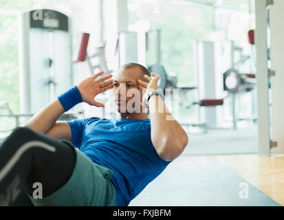 Focalizzato l'uomo facendo sit ups in palestra Foto Stock