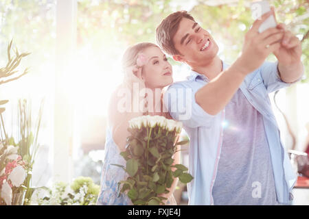 Giovane tenendo selfie al negozio di fiori Foto Stock