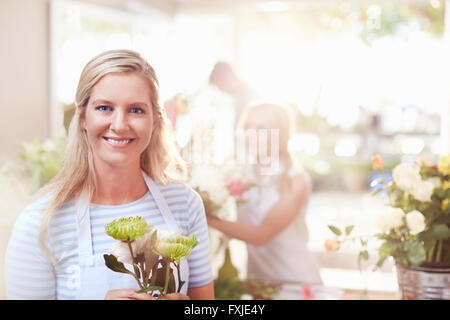 Ritratto sorridente fioraio azienda spider mamme in negozio di fiori Foto Stock